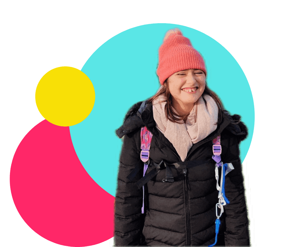 Girl with backpack and pink beanie smiling.