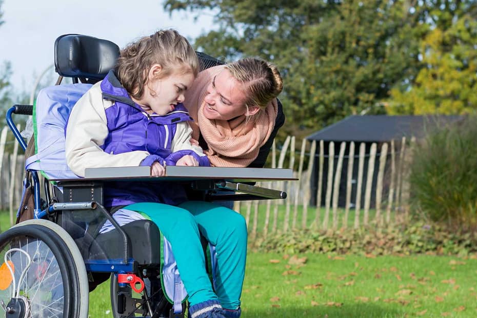 A woman playing with a young girl in a wheelchair